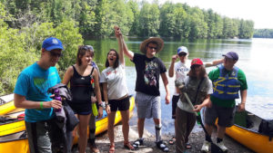 Out-tripping Adventure Camp - Campers pose on the shoreline by their canoes