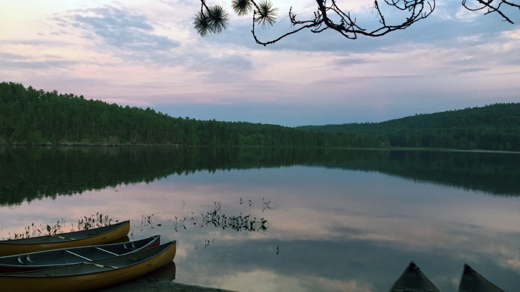 Out-tripping Adventure Camp - The lake with trees along the far shore and clouds overhead