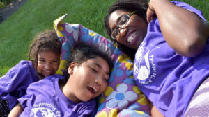Family Camp - A mother and daughters smile while lying on the grass